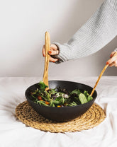 Natural olive wood spatula being used to mix a bowl of salad.